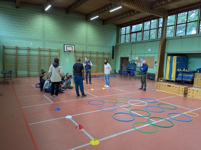 Ce visuel montre les élèves et les enseignants autour du parcours d'obstacles installé dans le gymnase.